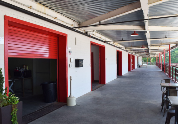 Row of red roll-up storage unit doors along a covered walkway