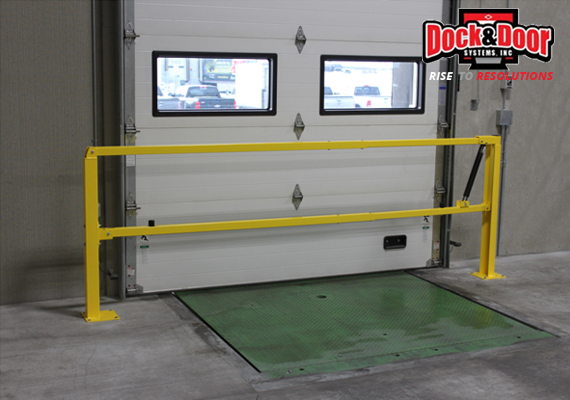Yellow safety gate arm across a dock leveler pit