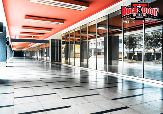 Row of air curtain units mounted along a glass-fronted commercial corridor