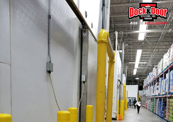 Cooler door assembly along a retail warehouse aisle with safety bollards