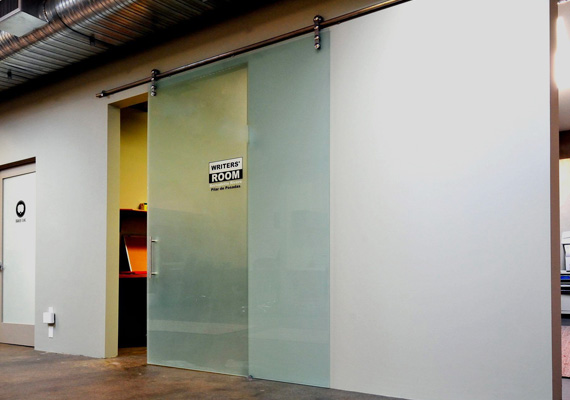 Frosted-glass sliding barn-style door on an exposed track in an office