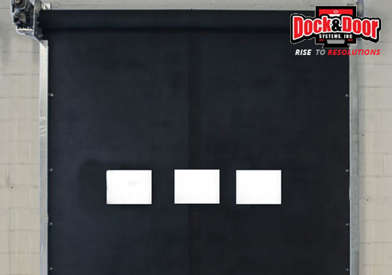 Black rubber swing door with clear vision panels in a warehouse opening