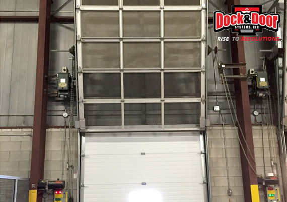 Overhead warehouse door with a mesh security screen above a sectional door panel