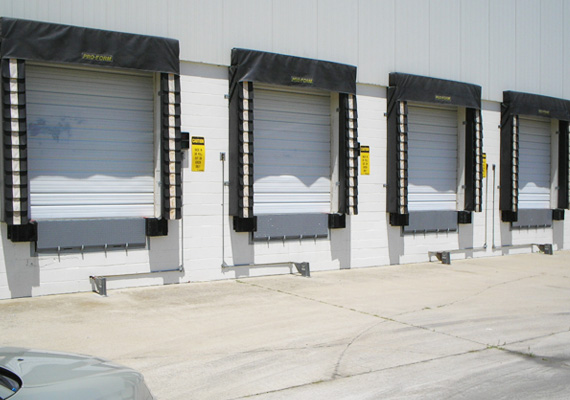 Row of loading dock doors with dock seals and restraint signage