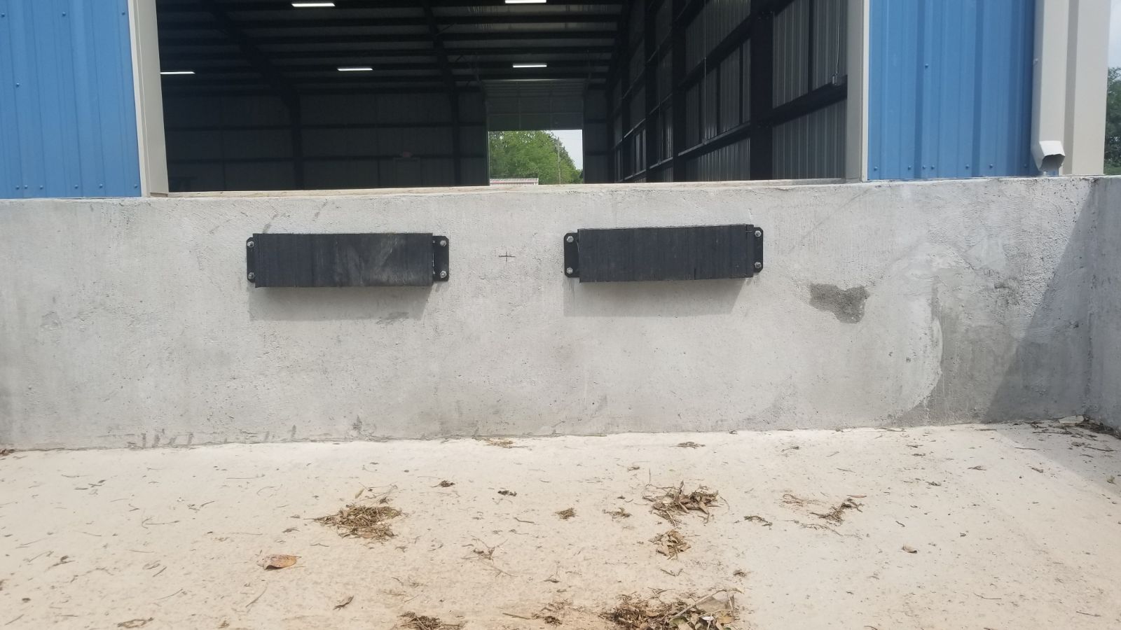 Two rubber dock bumpers mounted on a concrete loading dock edge