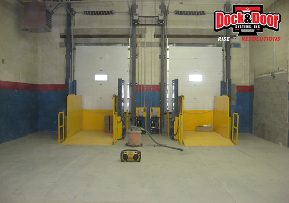 Two-post scissor lift dock levelers inside a warehouse loading area
