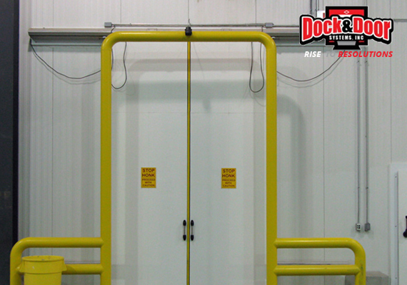Telescoping bi-parting fiberglass door with yellow guide rails at a loading dock